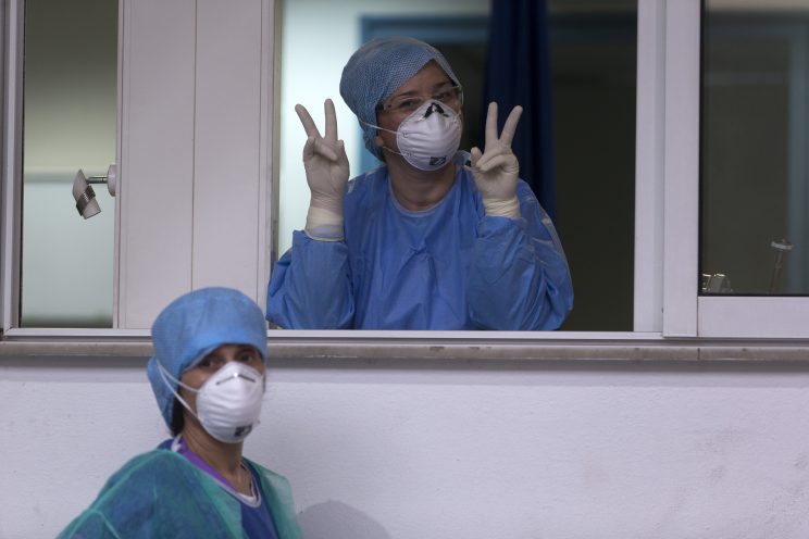 Nurses with PPE in Greece flash the peace sign