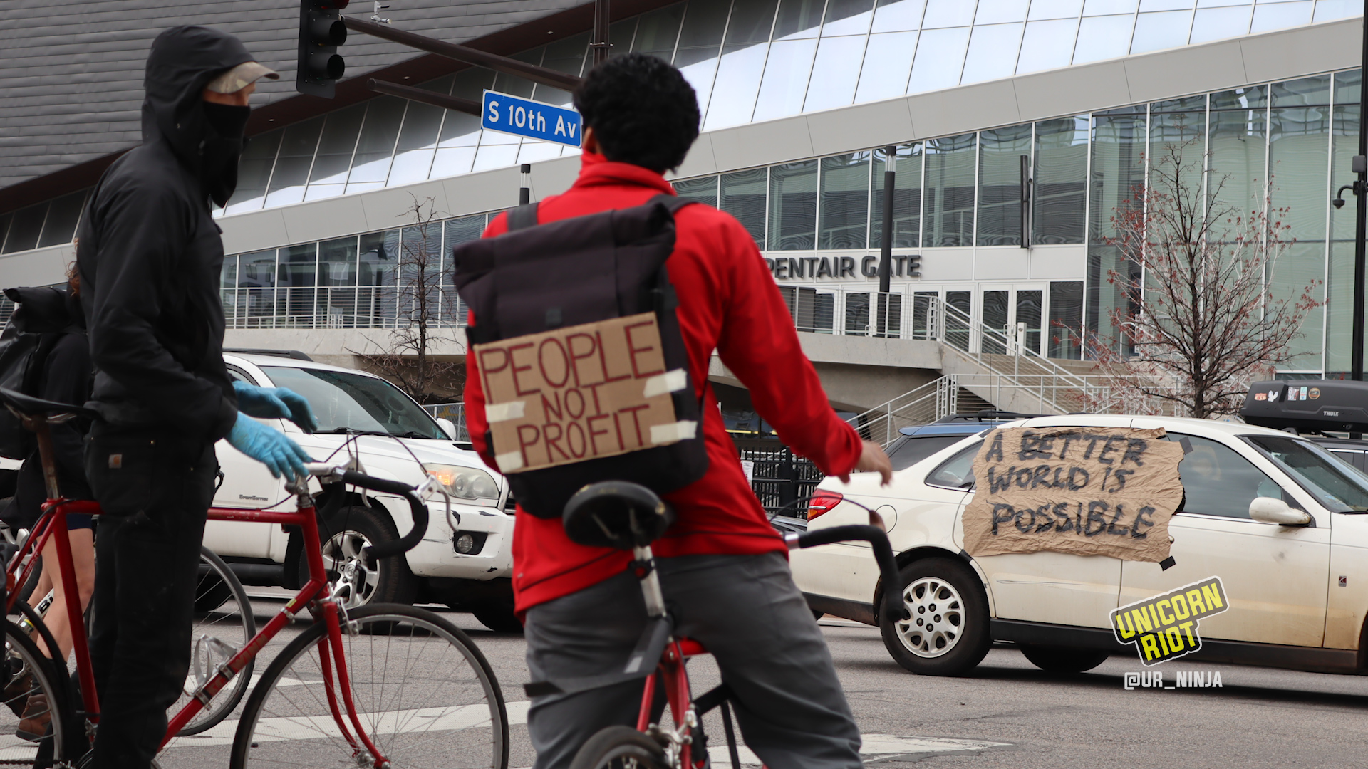 Bicyclists watch a caravan of cars on May Day