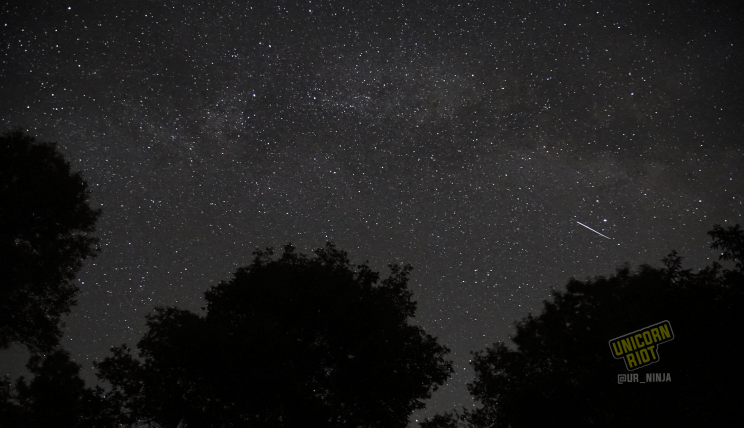 image: ten-second long exposure shot of the night sky facing East, in the northern hemisphere at midsummer. The nebulous arm of our spiral galaxy The Milky Way is visible stretching across the night sky from right to left in the image. A shooting star, seen in this image as a stretched-out point of white light, is visible on the right side of the sky, South-East.