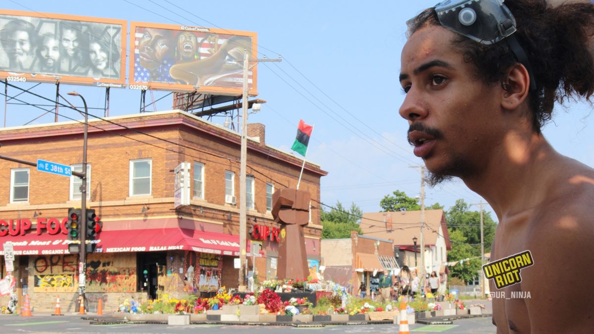 Youth looks west down 38th St. with the center of George Floyd Memorial Square in the background