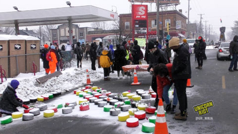 Crowd puts flowers on top of the letter X to commemorate Malcolm X on the 56th anniversary of his assassination
