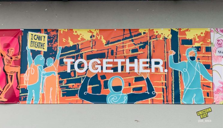 Mural features a scene of a burning building with protesters cheering, holding a sign that reads “I can’t breathe” across the street from the 3rd precinct police station which was torched by demonstrators / Photo by Marjaan Sirdar