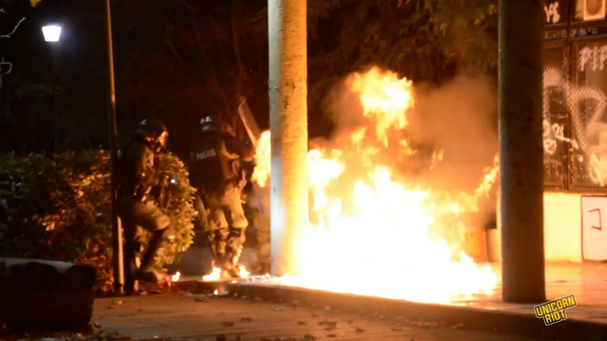 Riot police attempt to evade firebombs thrown at them on Nov. 17, 2022, during heavy clashes after the main demonstration against the former ruling military junta.