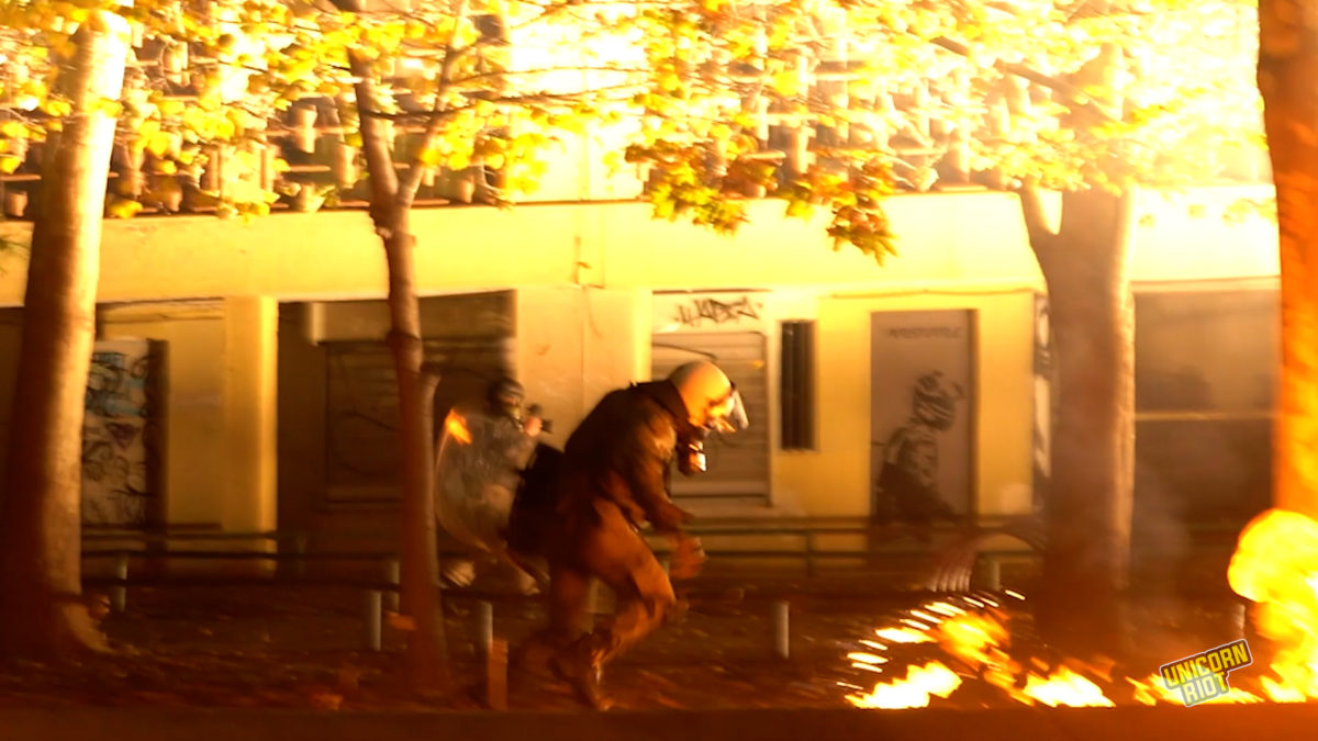 Riot police runs by fire at the Polytechnic University on Nov. 17, 2022, during heavy clashes after the main demonstration against the former ruling military junta.