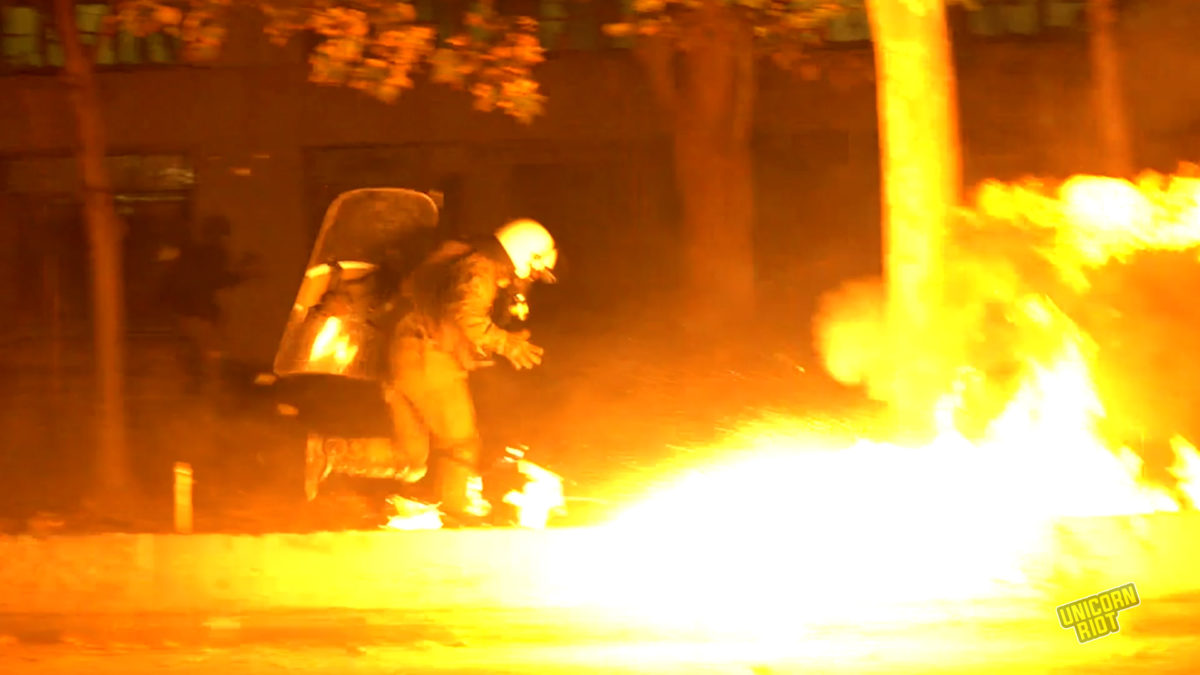 Riot police runs by a freshly exploded firebomb at the Polytechnic University on Nov. 17, 2022, during heavy clashes after the main demonstration against the former ruling military junta.
