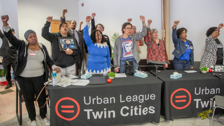 Families of those killed by police raise their fists as a meeting closes out with the UN at the Minneapolis Urban League on May 2, 2023.
